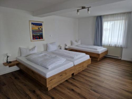 two beds in a room with wooden floors at Hotel Sonnenkeller in Neu-Ulm