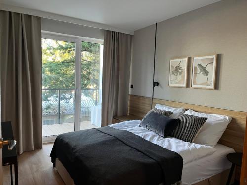 a bedroom with a bed and a large window at NATURA - luksusowy apartament ze Spa Dziwnów in Dziwnów