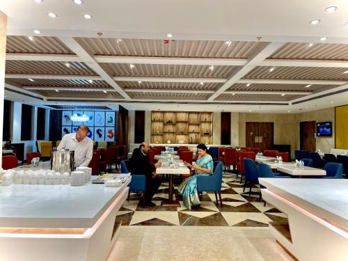 a restaurant with two people sitting at tables and a waiter at The Mars Resorts in Meerut