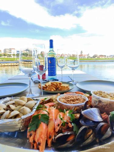 a table with plates of food and glasses of wine at Floating Experience - Casa flutuante a 25 min do Porto in Póvoa de Varzim