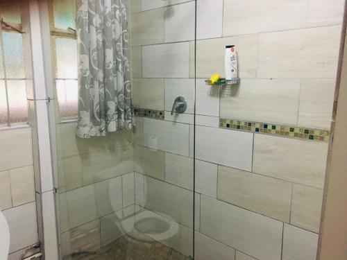 a shower with white tile in a bathroom at At Rest Place in Empangeni