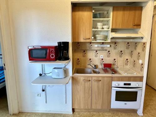 une petite cuisine avec un évier et un micro-ondes dans l'établissement Appartement 2 Pièces avec Mezzanine, 6 Couchages, Proche Plage à Argelès-sur-Mer - FR-1-225-272, à Argelès-sur-Mer