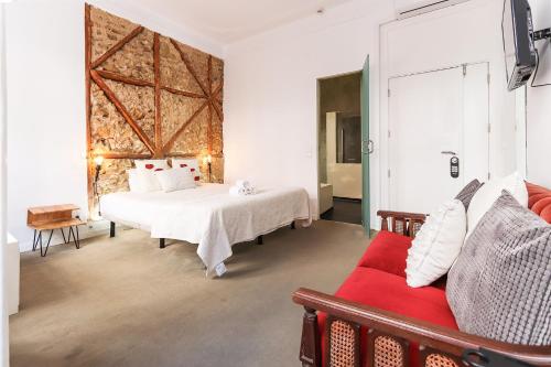 ein Schlafzimmer mit einem Bett und einem roten Sofa in der Unterkunft Chiado Prime Suites by Homing in Lissabon