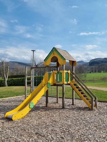 a playground with a yellow slide in a park at Camping Mayet-de-Montagne in Mayet-de-Montagne