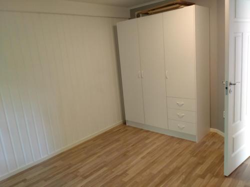 an empty room with white cabinets and a wooden floor at Sittesta 56 in Ösmo