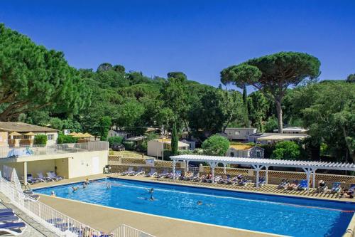 a large swimming pool with lounge chairs and trees at Bungalow luxe 3 chambres surplombant le Golf de St Tropez in Gassin