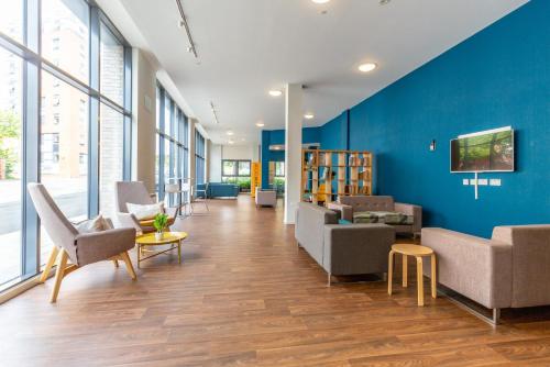 an office lobby with a blue wall and chairs at Ensuite Bedrooms with Shared Kitchen and Studios at Marshall Court in Newcastle in Newcastle upon Tyne