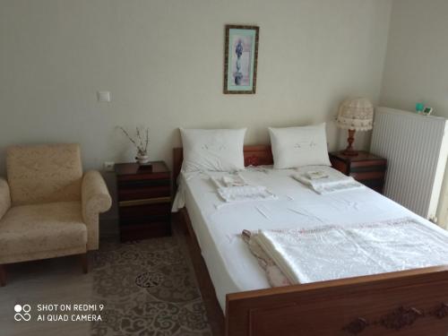 a bedroom with a large bed with a chair and a chair at BELLA-CAZA in Mákri