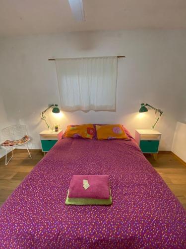 a bedroom with a purple bed with a napkin on it at casasomosamor in San Marcos Sierras