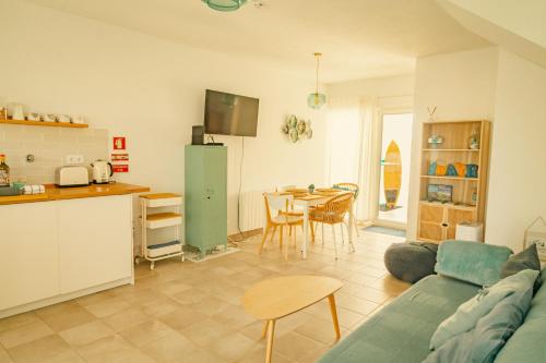 a kitchen and a living room with a couch and a table at Wayra Lodge [Samay] A different sunset every day in Raposeira