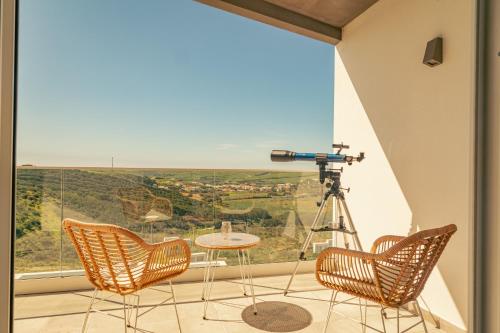 a camera and chairs on a balcony with a view at Wayra Lodge [Samay] A different sunset every day in Raposeira