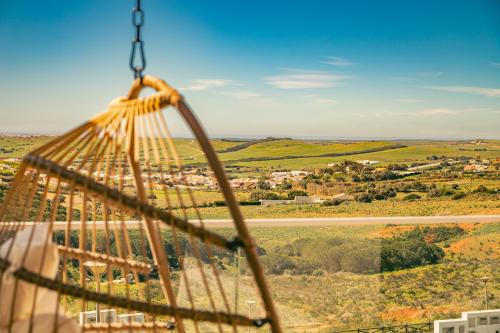 a hammock with a view of a city at Wayra Lodge [Samay] A different sunset every day in Raposeira
