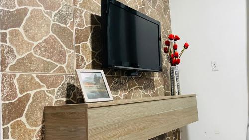 a flat screen tv on a stone wall with a picture at Montaña de Paz in San Ramón Sur