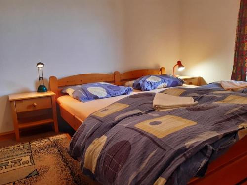 a bedroom with two beds and a night stand with a lamp at Chalupa pod Bukovou horou, Jizerské hory in Smržovka