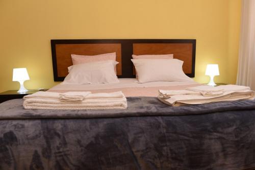 een bed met witte lakens en kussens en 2 lampen bij TMP Apartamento in Quarteira