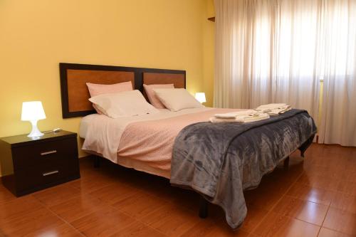 1 dormitorio con 1 cama grande y cabecero de madera en TMP Apartamento, en Quarteira