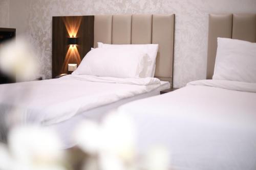 two beds in a hotel room with white sheets and pillows at The Castle Hotel in Amman