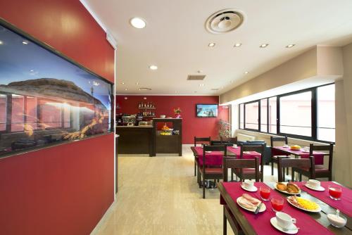 a restaurant with red walls and tables and chairs at Oasi Village Hotel in Milan