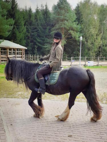 a woman is sitting on a black horse at FORMA Apartament Supraśl in Supraśl