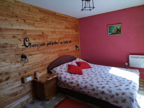 ein Schlafzimmer mit einem Bett und einer Holzwand in der Unterkunft Kuća za odmor Vilin vrt Vrnjacka Banja Otroci in Vrnjačka Banja