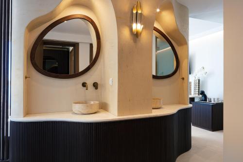 a bathroom with two sinks and two mirrors at Naiades Boutique Hotel - Adults Only in Elounda
