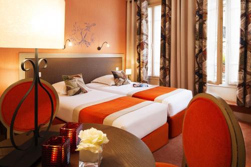 two beds in a hotel room with a table and chairs at Hotel Residence Foch in Paris