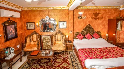 a bedroom with two beds and chairs in a room at WelcomHeritage Grace Hotel in Dharamshala
