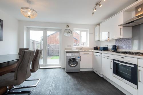 a kitchen with white cabinets and a washer and dryer at Thinford View in Spennymoor