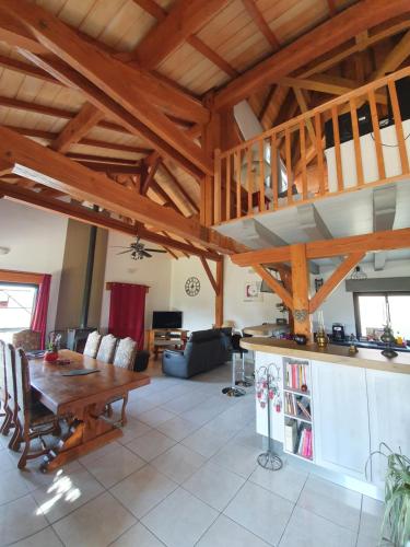 una gran sala de estar con techos de madera y una mesa. en Maison chaleureuse, en Grézels