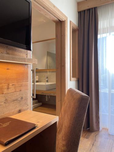 een kamer met een bureau met een stoel en een televisie bij Pension Moarhof in Feldthurns