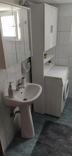 La salle de bains blanche est pourvue d'un lavabo et d'un miroir. dans l'établissement George's apartment Serres, à Serres