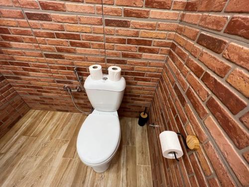 a bathroom with a toilet with a brick wall at Politkovskaia Apartment Tbilisi in Agaraki