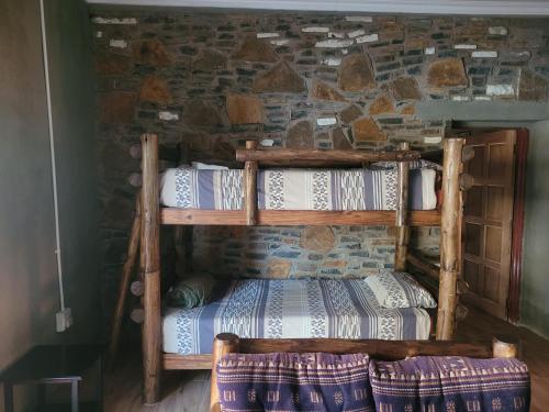 a wooden bunk bed in a room with a stone wall at Perdestal in Oranjeville