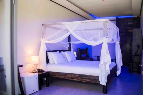 a bedroom with a white canopy bed with a lamp at Kingfisher Resort-Muhazi in Karagari