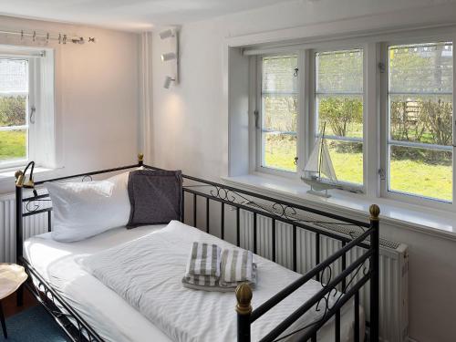 a bedroom with a bed with white sheets and windows at Friesenhaus Amrum Friesenhaushälfte *Klönschnack* in Süddorf