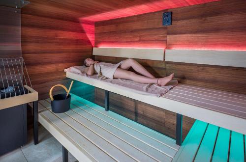 a woman laying on a bed in a sauna at Hi5-Hotel Seiersberg in Windorf