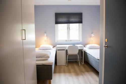 Habitación pequeña con 2 camas y escritorio. en Orsa Grönklitt, en Orsa