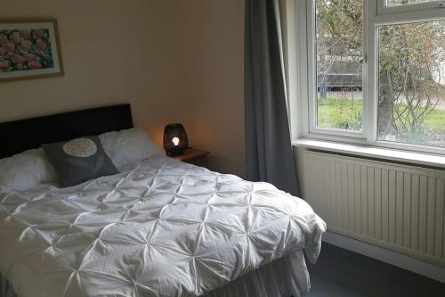 ein Schlafzimmer mit einem weißen Bett und einem Fenster in der Unterkunft A quiet self-contained flat close to Exeter. in Stoke Canon