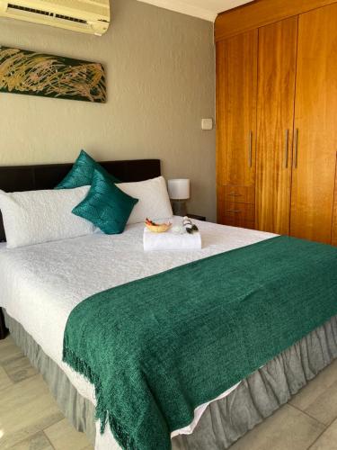 1 dormitorio con 1 cama grande con manta verde en Christa's Place 899, en Pretoria