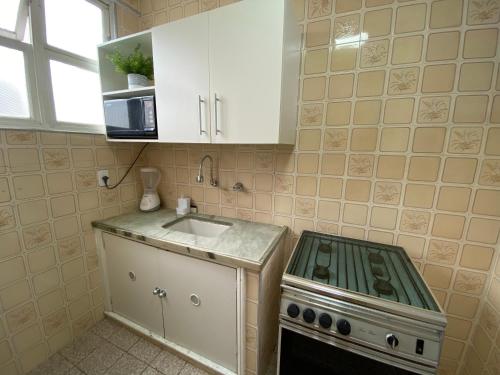 a small kitchen with a stove and a sink at Apartamento Frente à Praia Santos in Santos