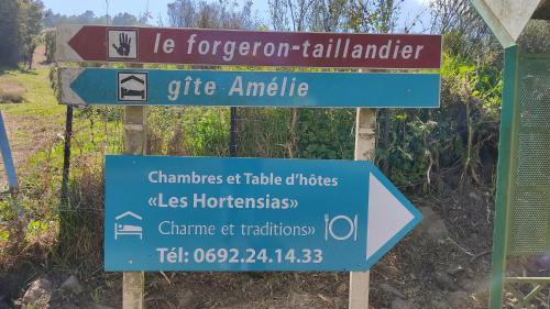 a blue sign in front of a field at Chambres et Table d'hôte Les Hortensias in La Plaine des Cafres