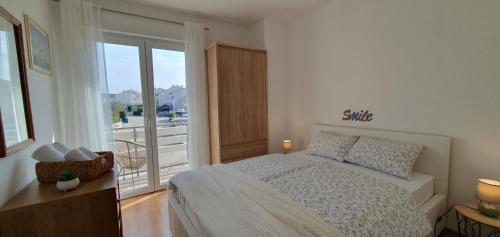une chambre avec un lit et une grande fenêtre dans l'établissement Apartmani Pavlović, à Krk