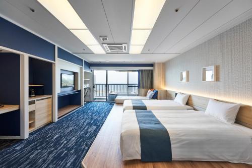 two beds in a hotel room with a balcony at il azzurri in Nishiizu