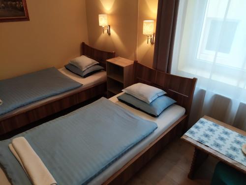 two beds in a small room with a window at Szilvia Panzió Gyomaendrőd in Gyomaendrőd