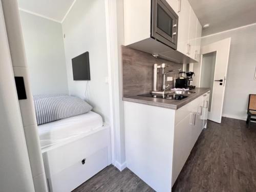 uma pequena cozinha com armários brancos e um lavatório em Duen12 21 Magic Beach em Westerland