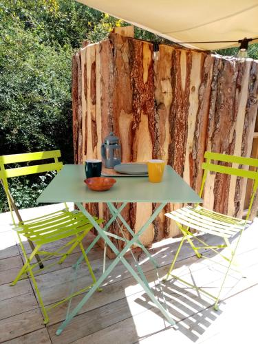 a table and chairs on a patio with a tree stump at Ecolodge de la Ferme du Chant de Cailloux in Die