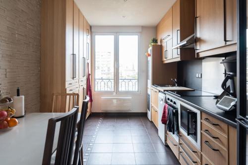 une cuisine avec une table et une grande fenêtre dans l'établissement Very luminous 73m with clear view, à Vincennes