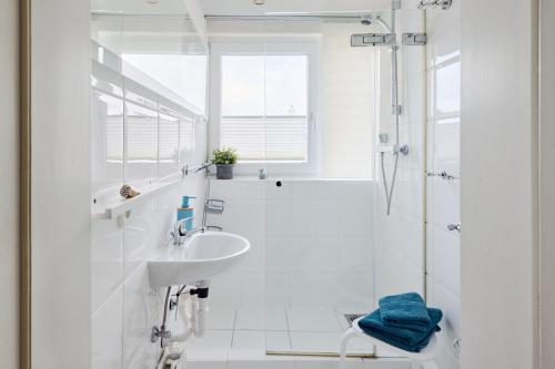 a white bathroom with a sink and a shower at Ferienwohnung Ostseeperle Moba-Travel in Travemünde