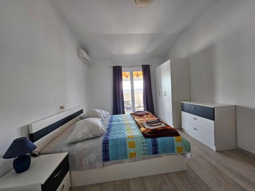 ein weißes Schlafzimmer mit einem Bett und einem Fenster in der Unterkunft Fam. Grce in Barbat na Rabu