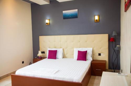 a bedroom with a large bed with pink pillows at IMOLEASE Kouessi Menontin in Cotonou
